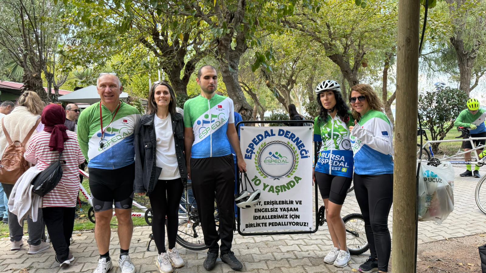 eşpedal ekibi bir parnkartın etrafındalar. pankartta eşit erişilebilir ve engelsiz yaşam ideallerimiz için birlikte pedallıyoruz yazıyor. 10.yıl kutlama pankartı.